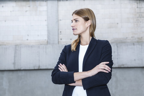 Porträt einer jungen Geschäftsfrau mit verschränkten Armen, lizenzfreies Stockfoto