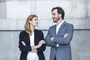 Two business people standing face to face with crossed arms - FMKF001754