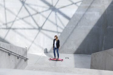 Geschäftsfrau mit rosa Skateboard in moderner Architektur - FMKF001735