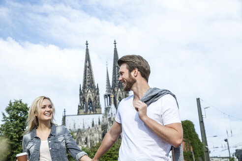 Germany, Cologne, happy young walking hand in hand - FMKF001758