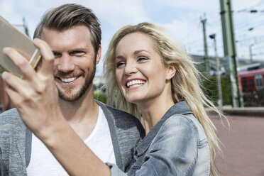 Germany, Cologne, young couple taking a selfie with smartphone - FMKF001760