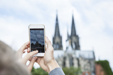 Deutschland, Köln, junge Frau fotografiert den Kölner Dom mit Smartphone - FMKF001836