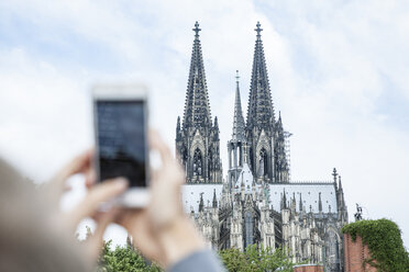 Deutschland, Köln, junge Frau fotografiert den Kölner Dom mit Smartphone - FMKF001763