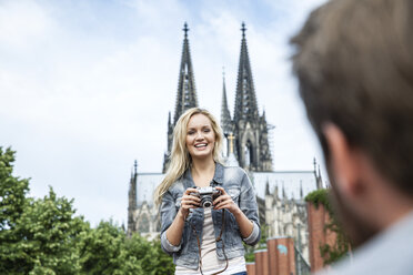 Deutschland, Köln, Porträt einer lächelnden Frau mit Kamera, die ihren Freund anschaut - FMKF001765