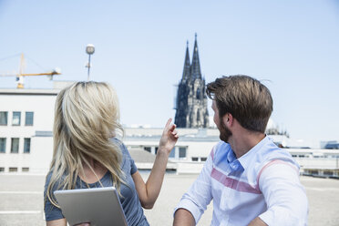 Germany, Cologne, young couple with digital tablet looking at Cologne Cathedral - FMKF001781