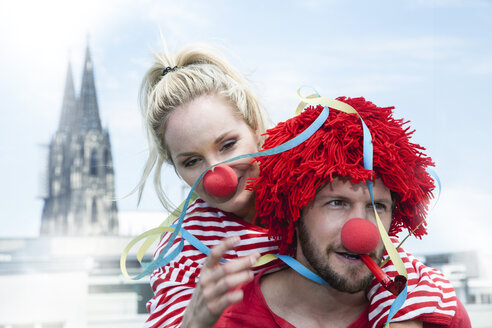 Germany, Cologne, young couple celebrating carnival dressed up as clowns - FMKF001785