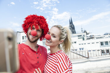 Germany, Cologne, young couple celebrating carnival dressed up as clowns - FMKF001788