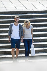 Deutschland, Köln, glückliches junges Paar geht die Treppe hinunter - FMKF001813