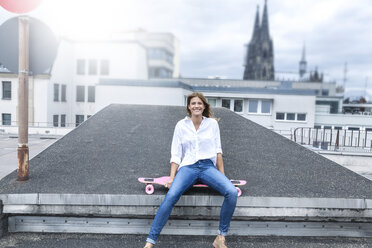 Deutschland, Köln, Porträt einer lächelnden jungen Frau auf einer Dachterrasse - FMKF001819