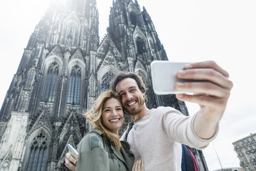 Deutschland, Köln, Porträt eines jungen Paares, das ein Selfie vor dem Kölner Dom macht - FMKF001828