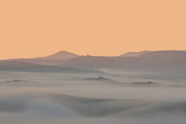 Italy, Tuscany, Val d'Orcia, view to rolling landscape at sunrise in the fog - LOMF000044