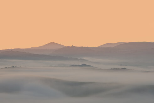 Italien, Toskana, Val d'Orcia, Blick auf hügelige Landschaft bei Sonnenaufgang im Nebel - LOMF000044