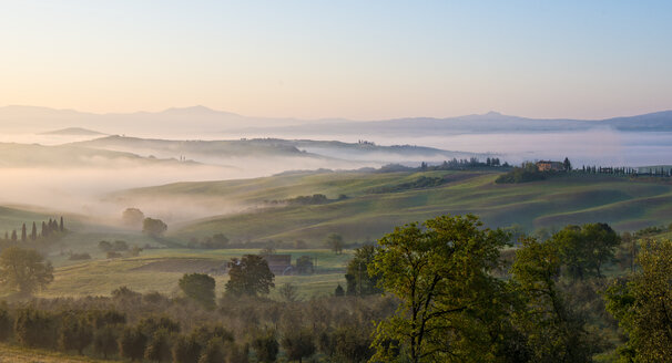 Italien, Toskana, Val d'Orcia, Blick auf hügelige Landschaft bei Sonnenaufgang im Nebel - LOMF000042