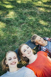 Three happy teenage friends lying on skateboard in meadow - AIF000076