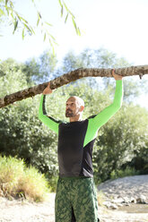 Man doing CrossFit exercise with tree trunk - MAEF010843