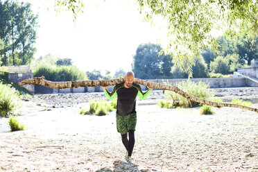 Man doing CrossFit exercise with tree trunk on his shoulders - MAEF010844