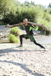 Man doing CrossFit exercise with tree trunk on his shoulders - MAEF010847