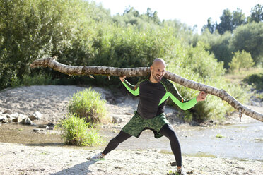 Man doing CrossFit exercise with tree trunk on his shoulders - MAEF010848