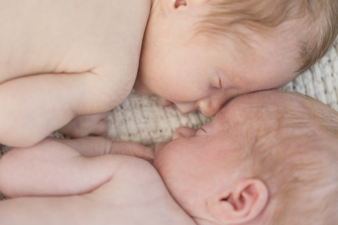 Neugeborene Zwillinge schlafen Kopf an Kopf, lizenzfreies Stockfoto