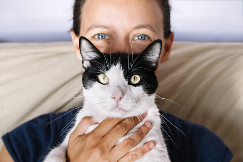 Blauäugige Frau hält eine schwarz-weiße Katze - GEMF000307