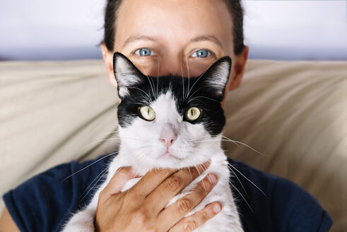 Blue eyed woman holding a black and white cat - GEMF000307