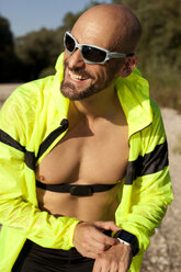 Selbstbewusster Mann in Sportkleidung stellt seine Smartwatch ein - MAEF010906