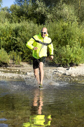 Mann in Sportkleidung läuft im Wasser - MAEF010871