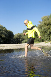 Mann in Sportkleidung läuft im Wasser - MAEF010872