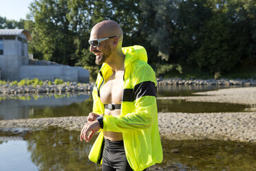 Selbstbewusster Mann in Sportkleidung stellt seine Smartwatch ein - MAEF010877