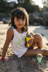 Spanien, Llanes, Porträt eines kleinen Mädchens, das am Strand mit Sand spielt - MGOF000427