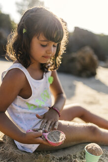 Spanien, Llanes, kleines Mädchen spielt mit Sand am Strand - MGOF000429