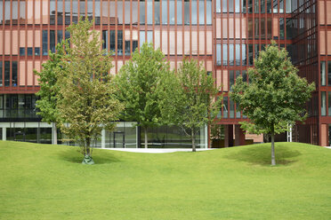 Deutschland, Hamburg, Blick auf die Fassade eines Bürogebäudes in der Hafencity mit Bäumen und Wiese - GUFF000132