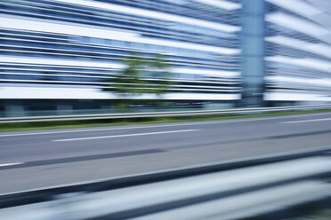 Germany, blurred office building with urban motorway in the foreground - GUFF000134