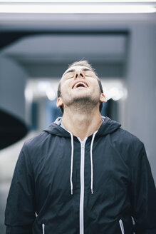 Portrait of man with head back wearing black hooded jacket - BZF000180