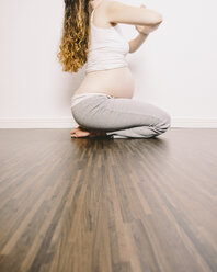 Schwangere Frau in Yoga-Position auf Holzboden - KRPF001624