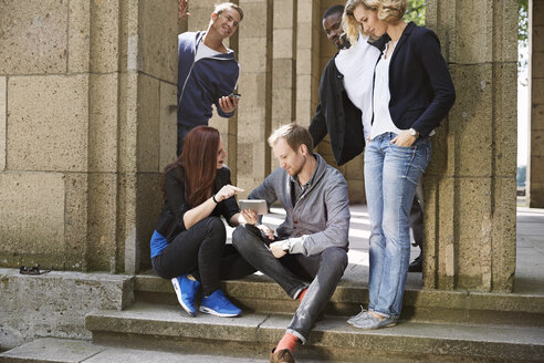 Gruppe von Freunden im Freien, die sich ein digitales Tablet teilen - STKF001393