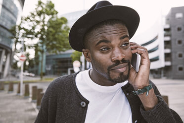 Young man on the phone wearing hat outdoors - STKF001396