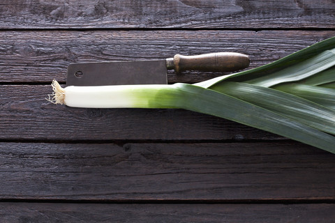 Lauch und Küchenbeil auf dunklem Holz, lizenzfreies Stockfoto