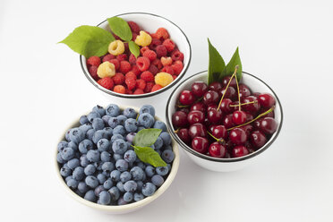 Three bowls of sour cherries, raspberries and blueberries on white ground - CSF026134