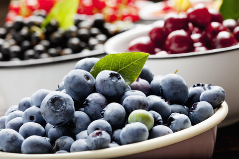 Schale mit Heidelbeeren und Schalen mit anderen Früchten im Hintergrund, lizenzfreies Stockfoto