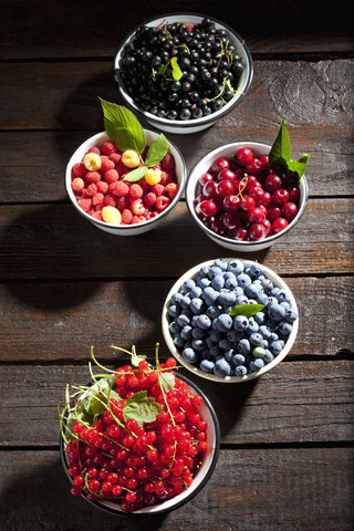 Bowls of sour cherries, raspberries, red and black currants and blueberries stock photo