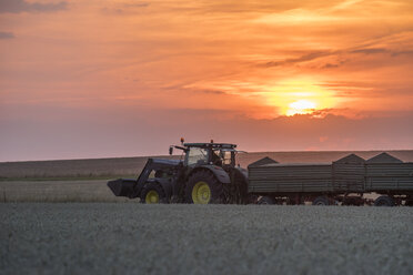 Deutschland, Niedersachsen, Traktor fährt bei Sonnenuntergang über ein Feld - PVCF000615