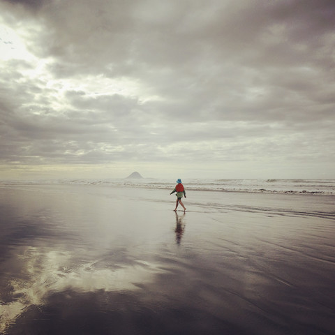 Neuseeland, Bay of Plenty, Ohope Beach, Frau geht am Strand entlang, Mount Waleback im Hintergrund, lizenzfreies Stockfoto