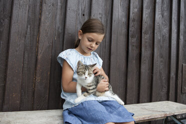 Mädchen mit Katze auf einer Bank sitzend - RBF003458