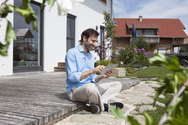 Lächelnder Mann mit digitalem Tablet auf einer Terrasse - RBF003461