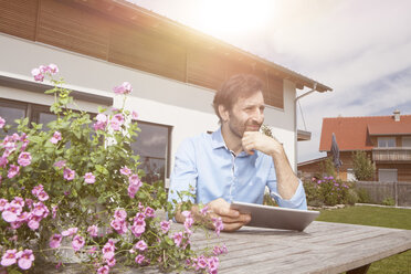 Mann mit digitalem Tablet im Garten - RBF003463