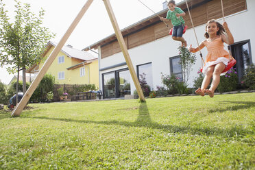 Brother and sister on a swing in garden - RBF003432