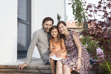 Portrait of smiling family with daughter sitting on terrace - RBF003482