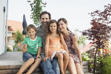 Porträt einer lächelnden vierköpfigen Familie auf der Terrasse - RBF003483