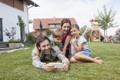 Smiling family of four in garden with cell phone stock photo